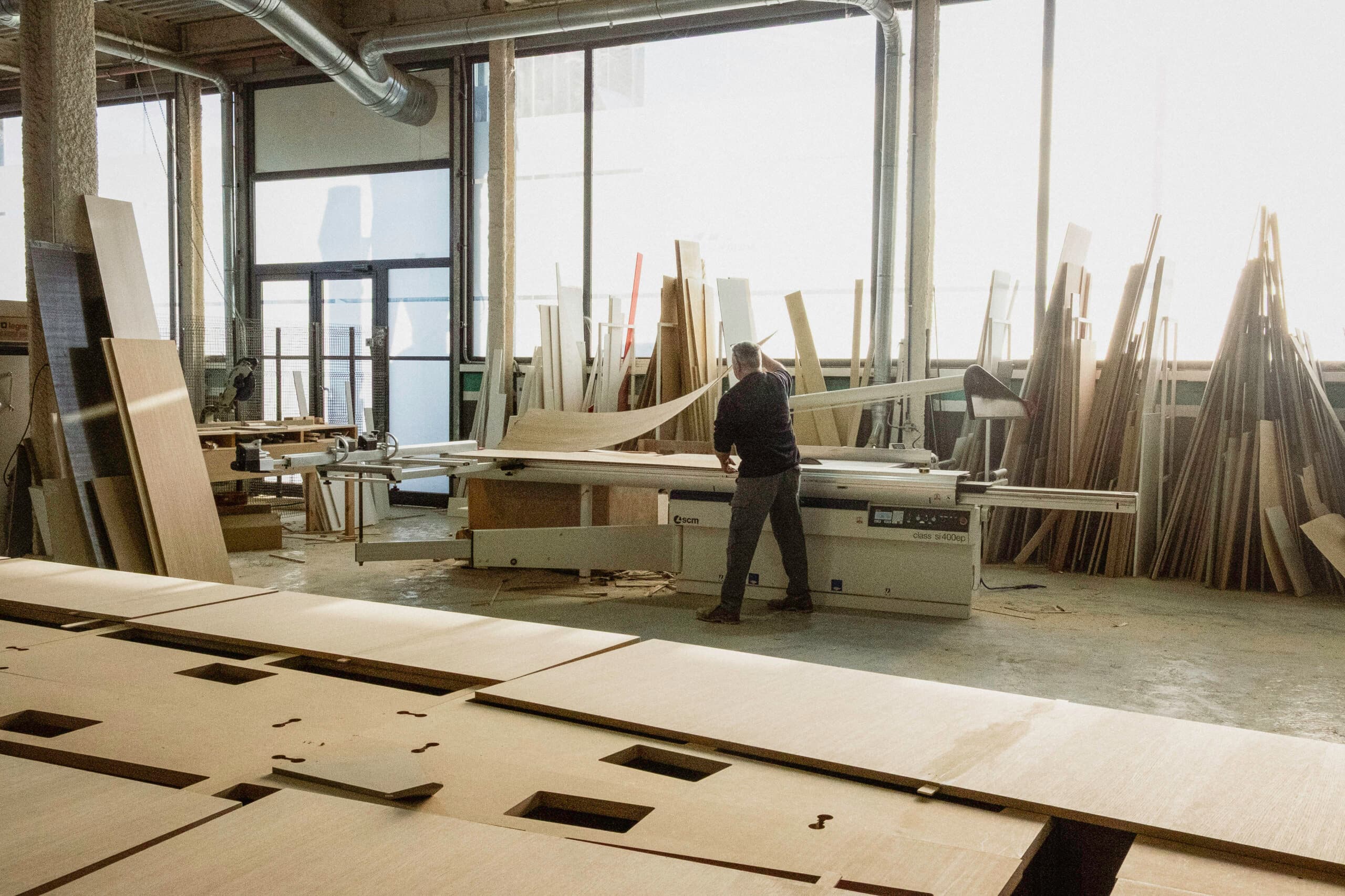 Craftsman cutting wood panels on a sliding saw at the KZ Bespoke workshop