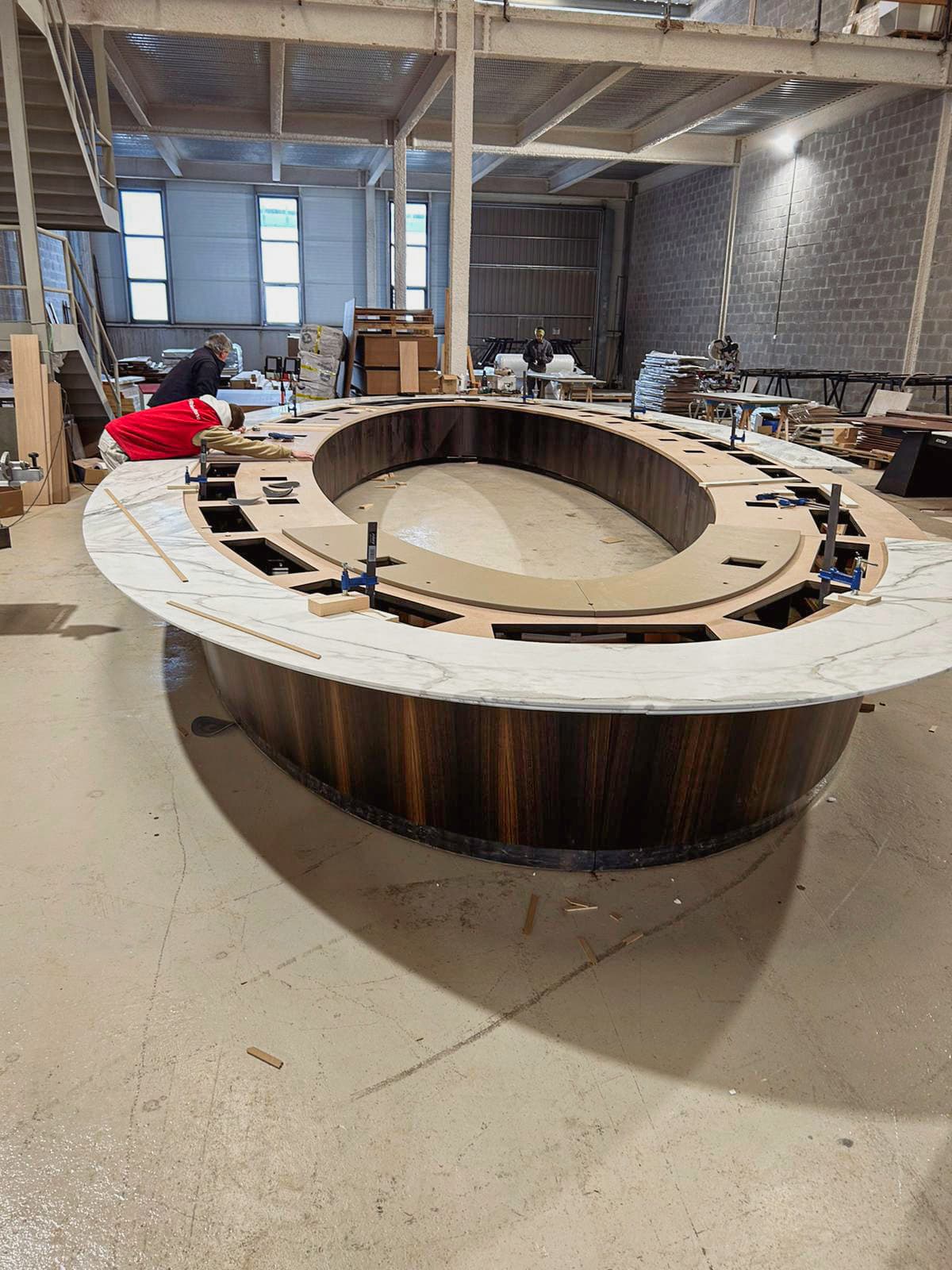 Craftsmen assembling a large round marble conference table in the KZ Bespoke factory